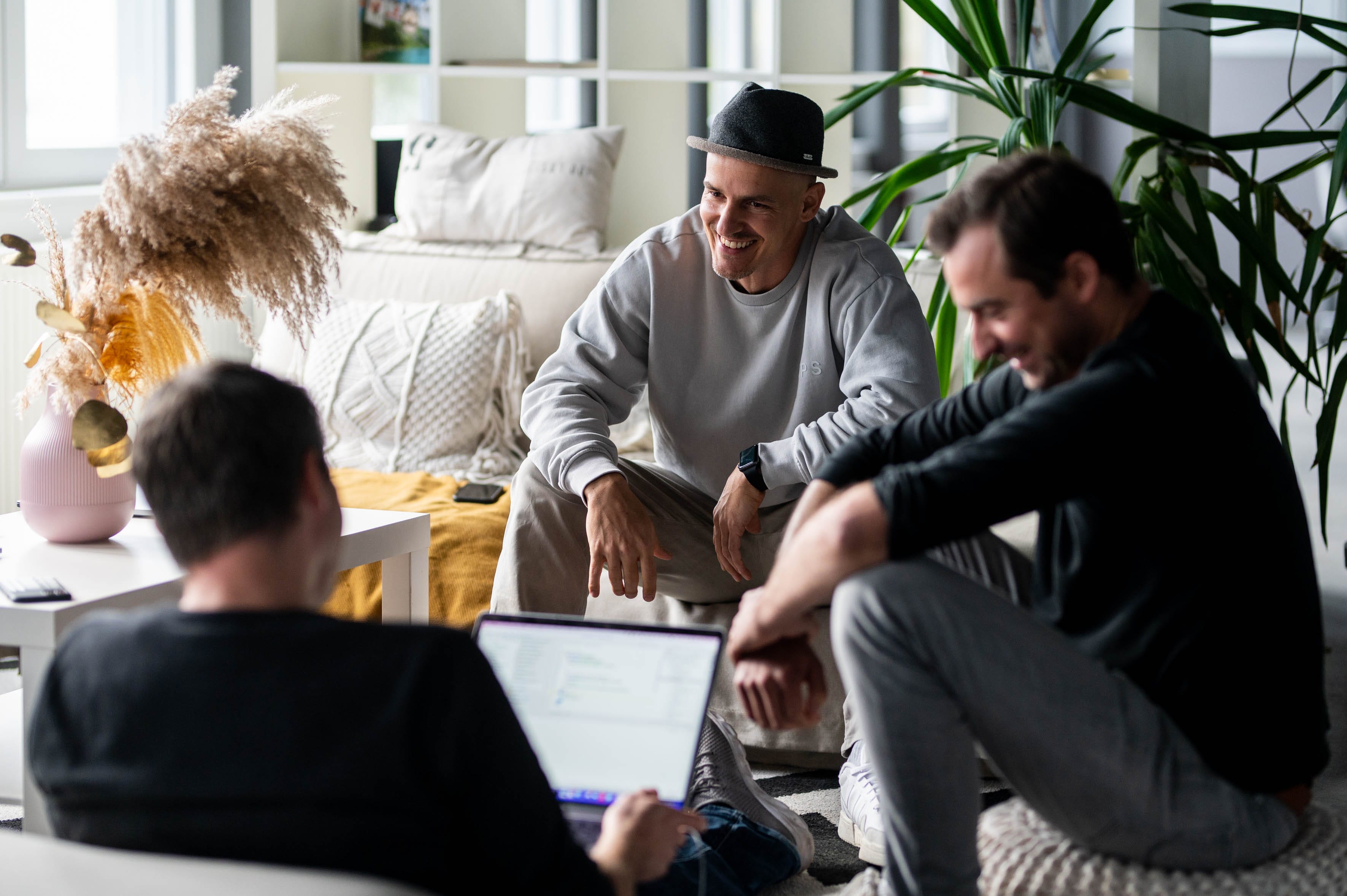 Drei Mitarbeiter einer Digitalagentur sitzen im Büro zusammen und besprechen ein Projekt