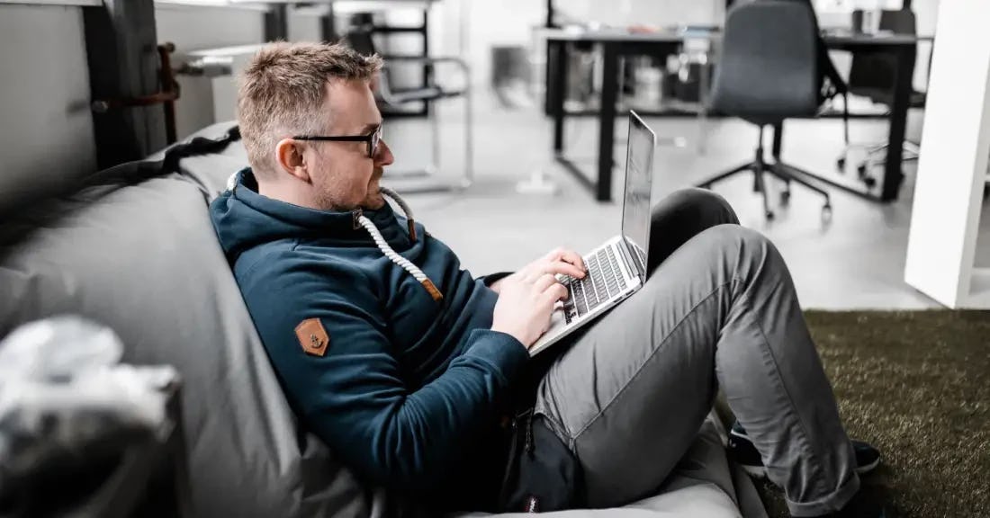 Ein Entwickler von VOLL sitzt mit seinem Macbook auf einem Sitzkissen im Büro.